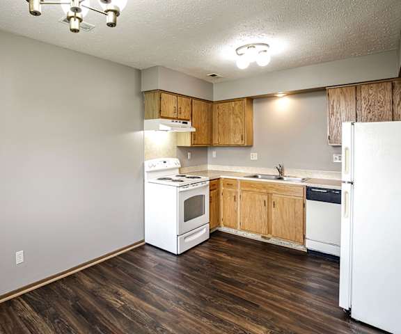 A kitchen with white appliances and wooden cabinets.
