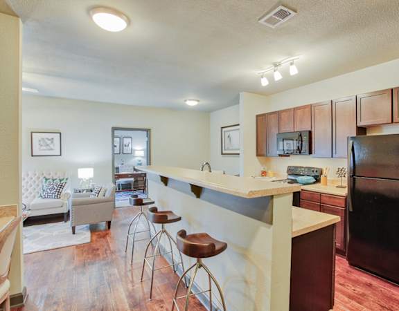 the view of a kitchen with a bar and a living room
