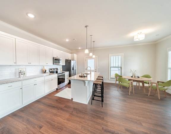 A kitchen with white cabinets and a wooden floor.