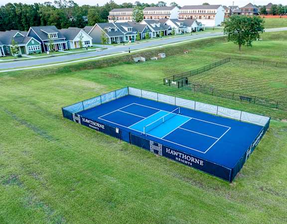 a blue tennis court in the middle of a grass field