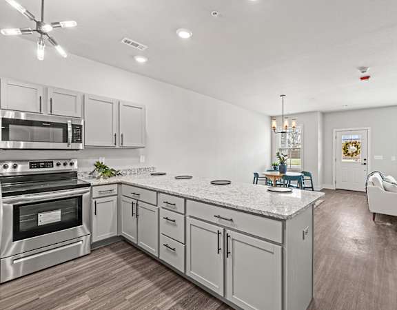 an open kitchen and living room with white cabinets and stainless steel appliances