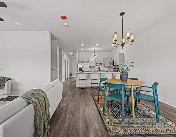 A modern living room with a grey couch and a wooden dining table.