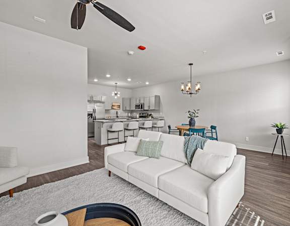 a living room with a white couch and a ceiling fan