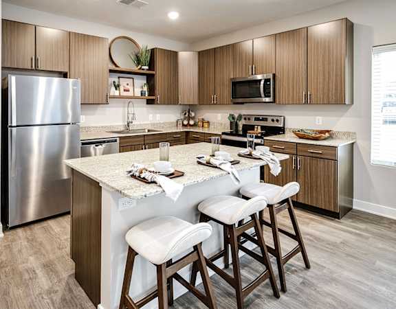 spacious kitchen with stainless steel appliances and a large island with 3 bar stools