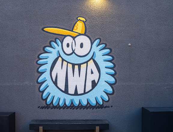 a painting of a blue monster with a yellow hat on a wall