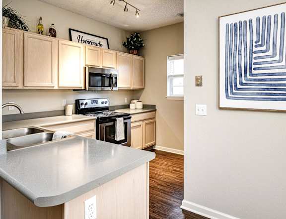 A kitchen with a stove top oven and a microwave at Autumn Grove Apartments, Omaha