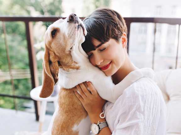 A woman is hugging a dog on a balcony.
