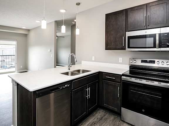 A modern kitchen with dark wood cabinets and stainless steel appliances.