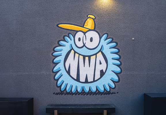 a mural of a monster with a yellow hat on a blue wall
