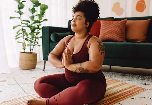 A woman in a red outfit is meditating on a yoga mat.