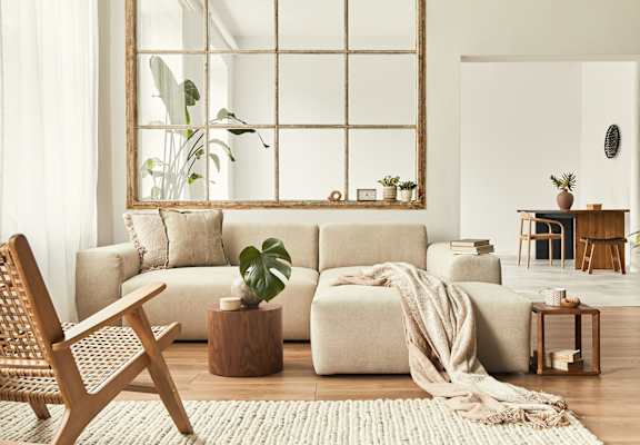 A living room with a large mirror, a wooden chair, a beige sofa, and a rug.