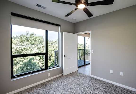 A room with a ceiling fan and a door leading to a balcony.