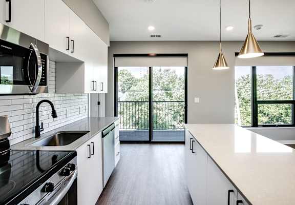 A modern kitchen with white cabinets and a black stove top oven.