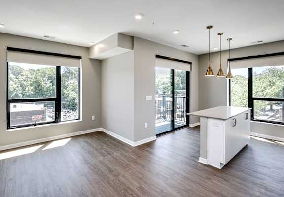 A spacious kitchen with a white island and pendant lights.
