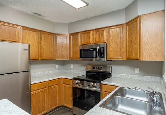 a kitchen with wood cabinets and black appliances and a stainless steel sink