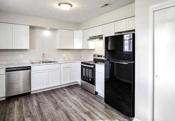 A kitchen with black appliances and white cabinets.