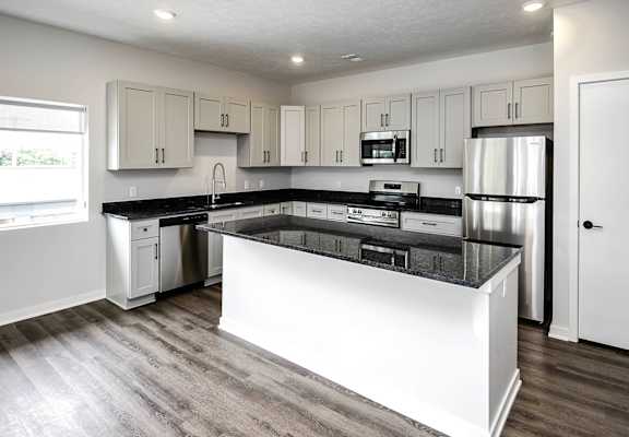a kitchen with white cabinets and a black counter top
