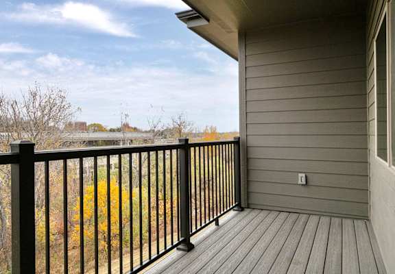 A balcony with a black railing and a grey wall.
