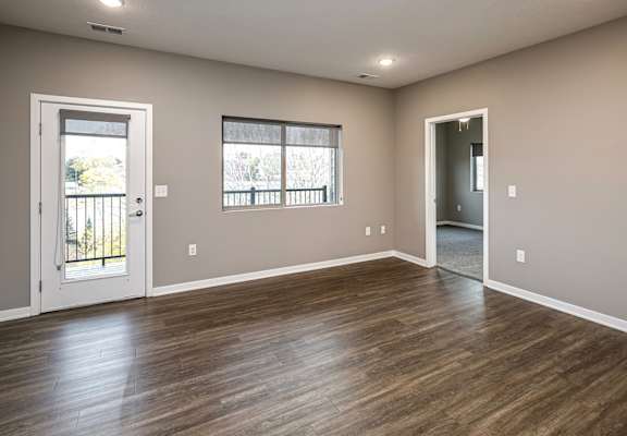 A room with a wooden floor and a door leading to a balcony.