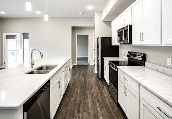 A modern kitchen with white cabinets and a black fridge.