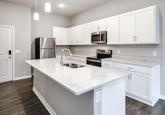 A kitchen with white cabinets and a marble countertop.