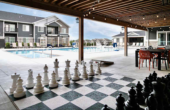 a large chess board in front of a swimming pool