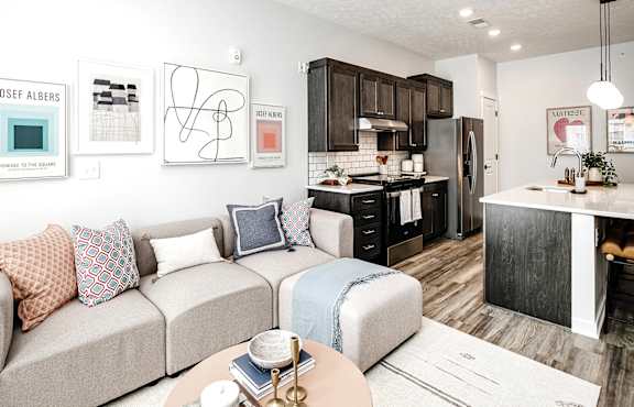 A modern living room with a couch, coffee table, and kitchen area.