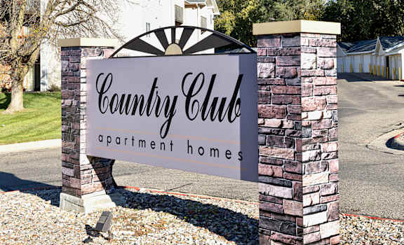 A sign for Country Club apartment homes stands in front of a building.