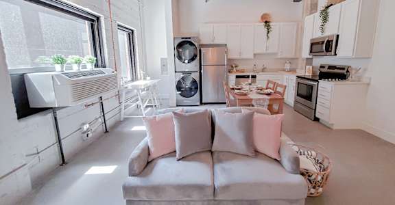 A modern kitchen with a grey couch and a window.