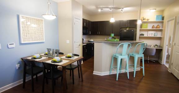A kitchen with a table set for two with a blue wall behind it.