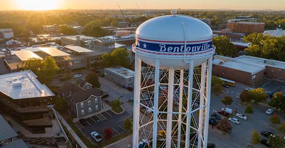 a water tower in the middle of a city at sunset