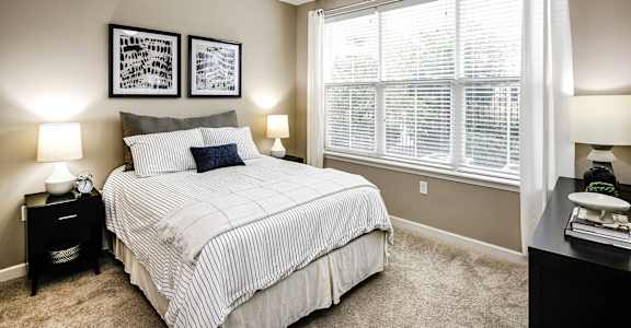 A bedroom with a bed, nightstands, and pictures on the wall.