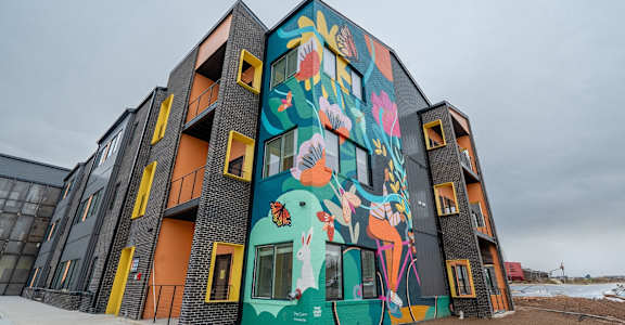 A building with a mural of a woman riding a bicycle on the side.
