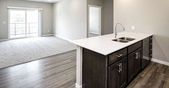 an empty kitchen and living room with a sink and a window