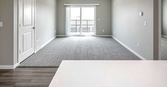 A spacious room with a carpeted floor and a large window.