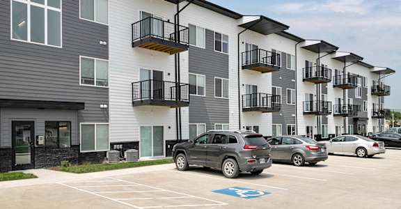 a row of apartment buildings with cars parked in front of them