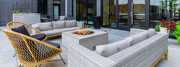 A patio with a black and yellow chair and a grey and white sofa.