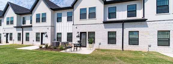 a large white building with a yard and a table and chairs
