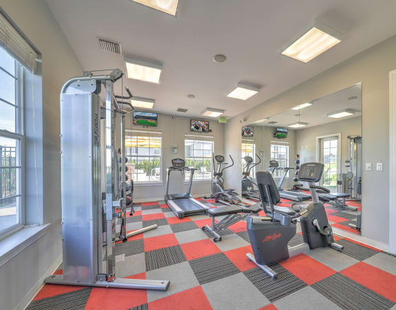 a spacious fitness center with cardio equipment and windows