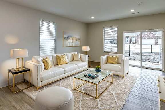 A living room with a white sofa, a glass coffee table, and a white ottoman at Sandstone Villas Apartments, Omaha, NE 68116