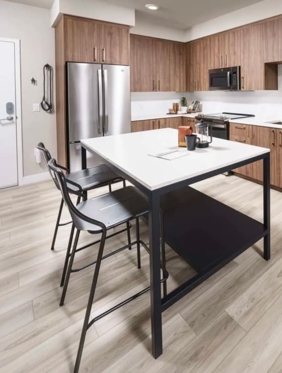 a kitchen with wooden cabinets and a white table with two chairs at NoMa Apartments, California, 94596