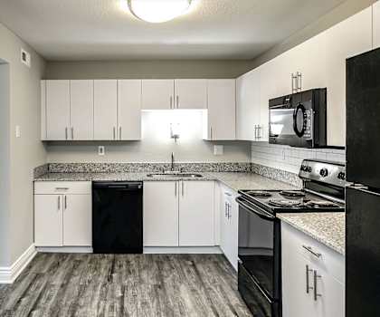 a kitchen with white cabinets and black appliances