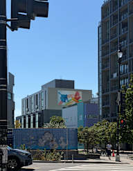 A street view with a car, a mural, and a building.