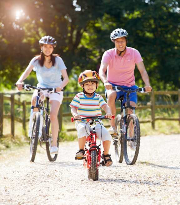 A family of three riding bikes on a gravel path at Queen St East in Scarborough, ON