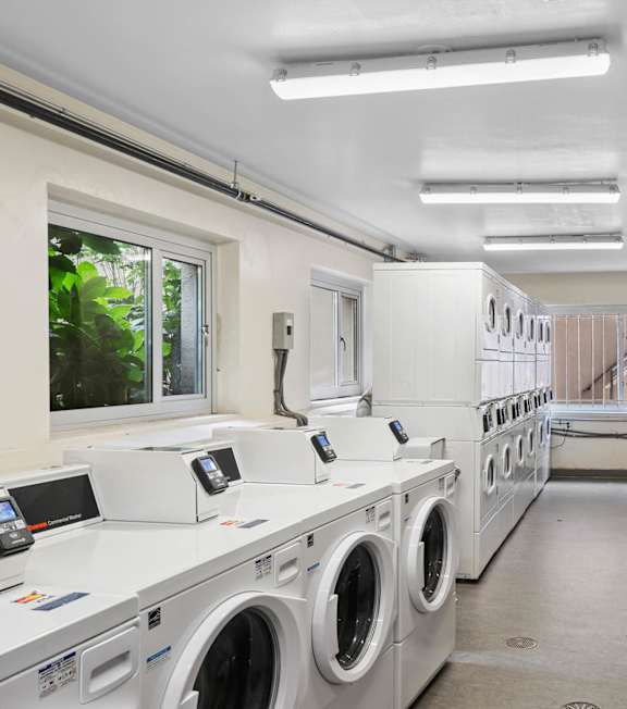 a laundry room with washers and dryers and a row of washing machines
