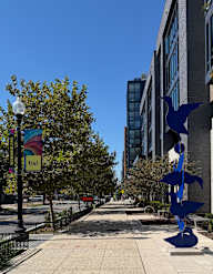 A blue sculpture of a bird is on the sidewalk.