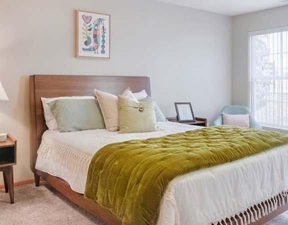 Large bedroom with queen sized bed, night stands, and bay window sitting area