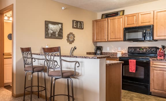 Kitchen with matching all black appliances and wooden cabinets at The Grand Legacy Apartments in Northwest Omaha, Nebraska
