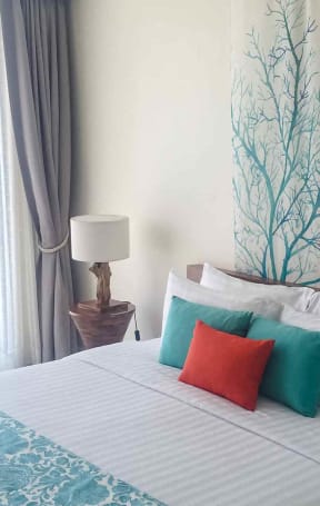 a bedroom with a bed with pillows and a painting on the wall