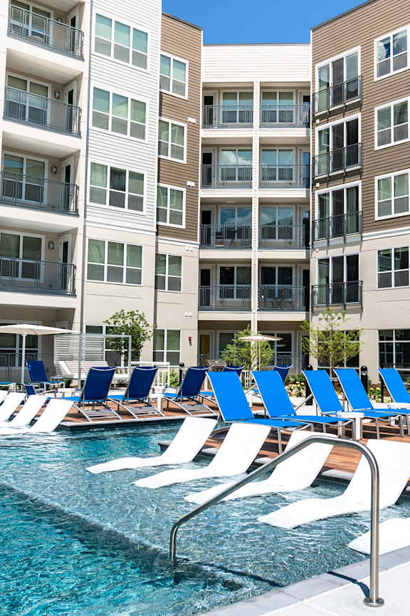 A pool with blue chairs and a building in the background. at Encore at Forest Park Apartments, Saint Louis, MO